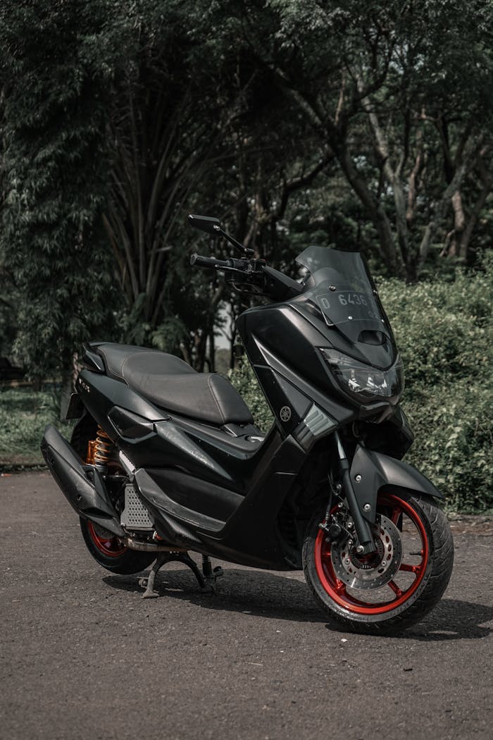 Stylish black Yamaha scooter parked on forest path, perfect for adventure enthusiasts.